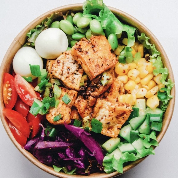 Colorful bowl with vegetables, grains, and herbs