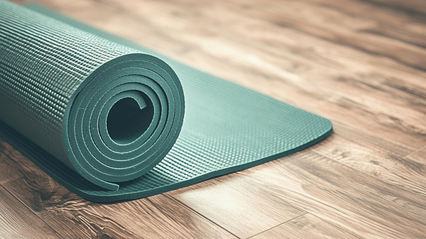 Rolled neutral yoga mat on a wooden floor